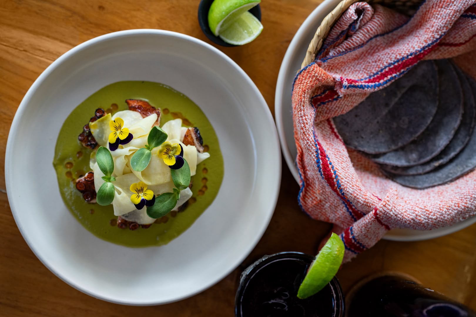 Overhead shot of a plated octopus dish with edible flowers